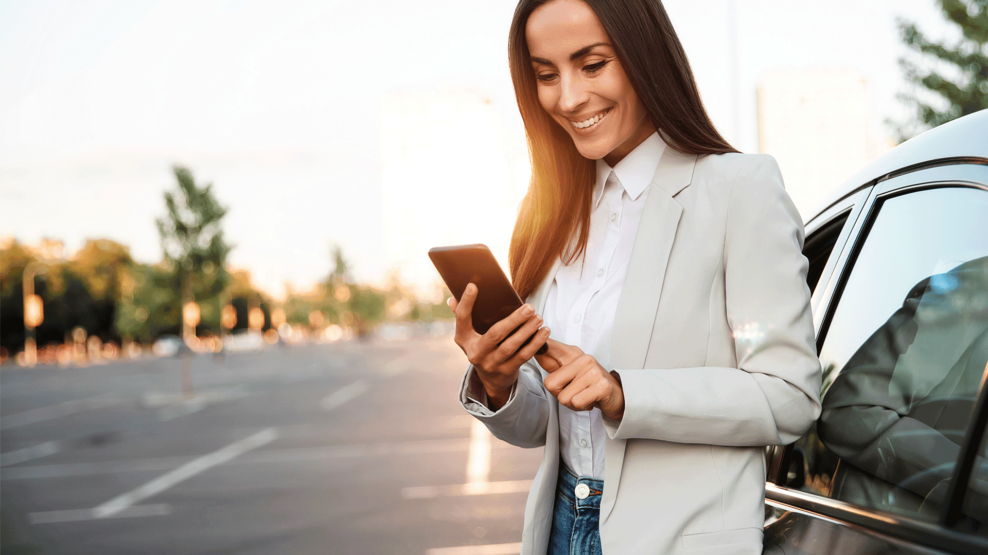 Une professionnelle utilise un téléphone intelligent alors qu’elle se tient à côté d’un véhicule. Une professionnelle utilise un téléphone intelligent alors qu’elle se tient à côté d’un véhicule.