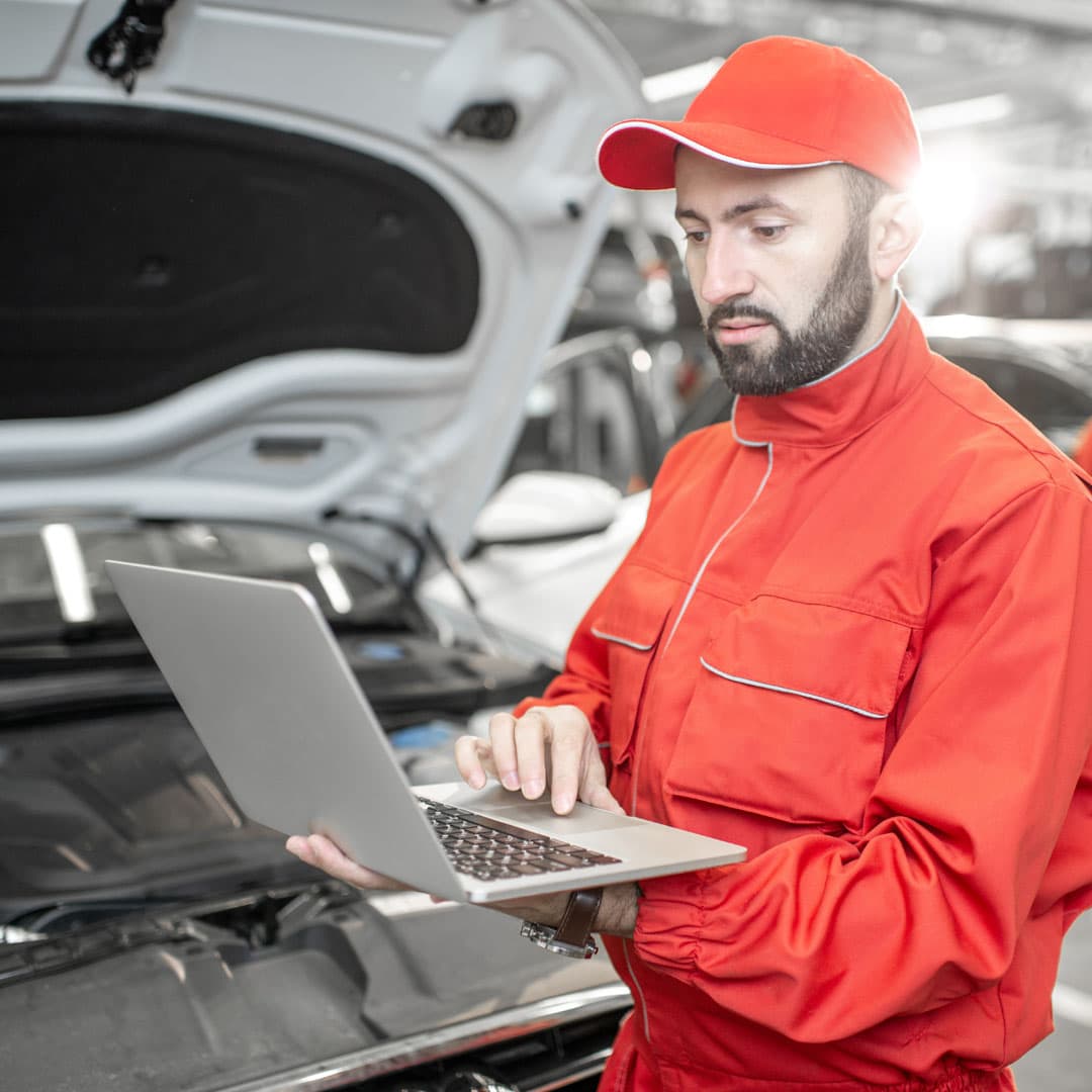 Auto mechanics using a laptop to perform vehicle diagnostics in a repair shop. Auto mechanics using a laptop to perform vehicle diagnostics in a repair shop.