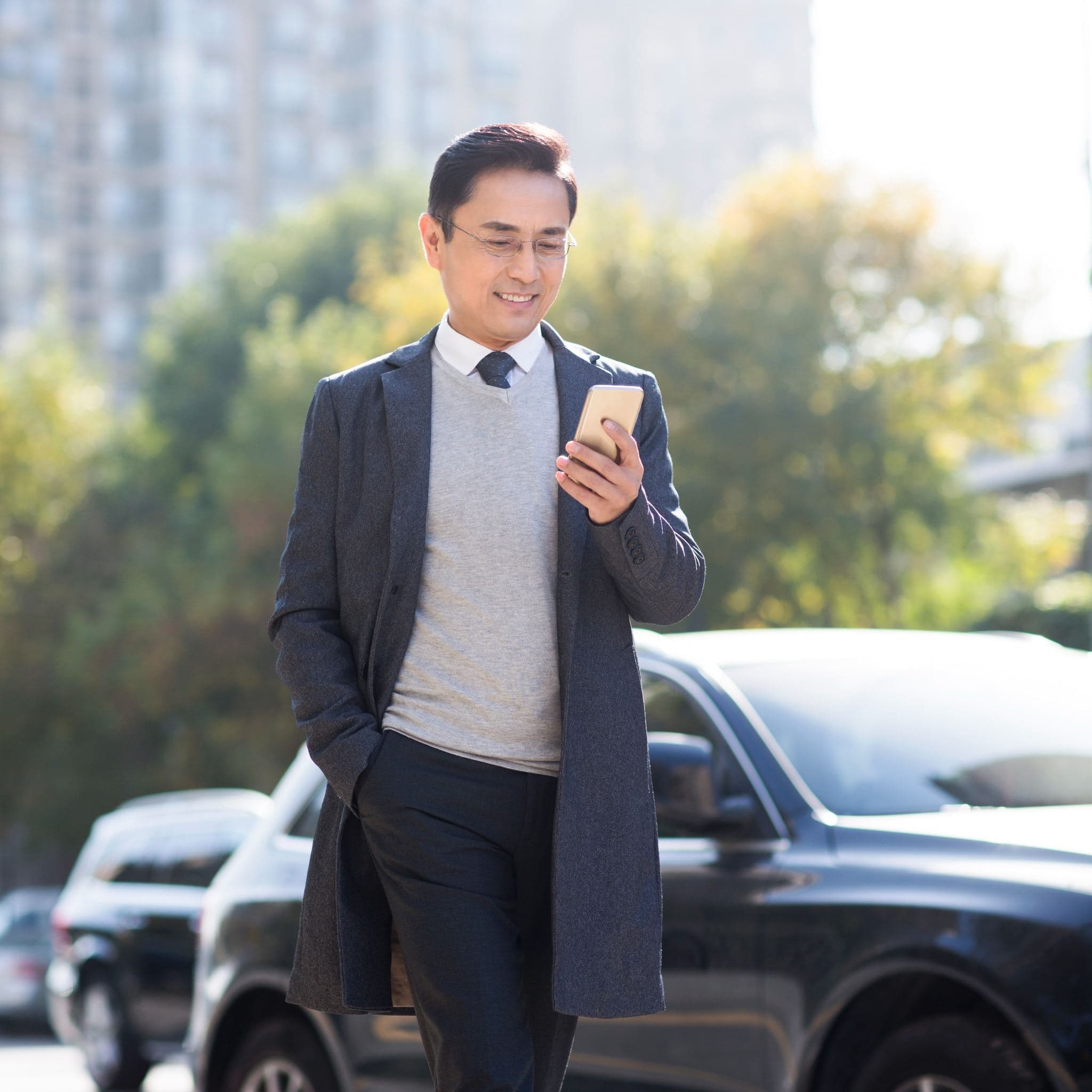 Un homme d’affaires utilise un téléphone intelligent alors qu’il se tient à côté d’un véhicule. Un homme d’affaires utilise un téléphone intelligent alors qu’il se tient à côté d’un véhicule.
